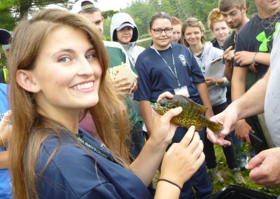 Girl holding a fish while group looks on