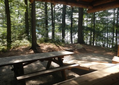 A view from inside of a lean-to, looking at a picnic table and ramp.