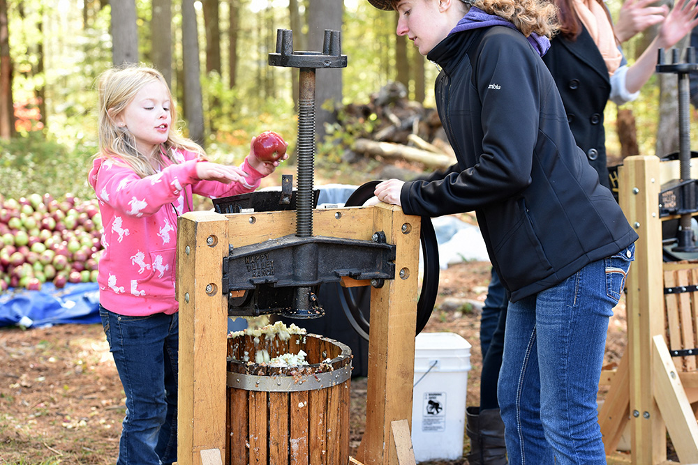 A young girl making cider.