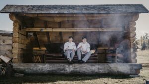 Two people sitting in a lean to with plates of food