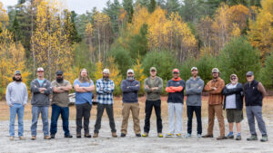 11 men standing in front of a fall backdrop