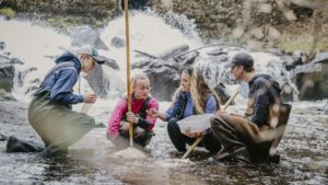 Four people crouching in a stream