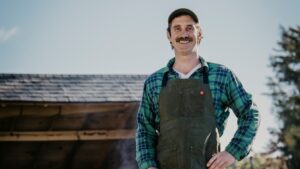 A man standing with an axe by a leanto