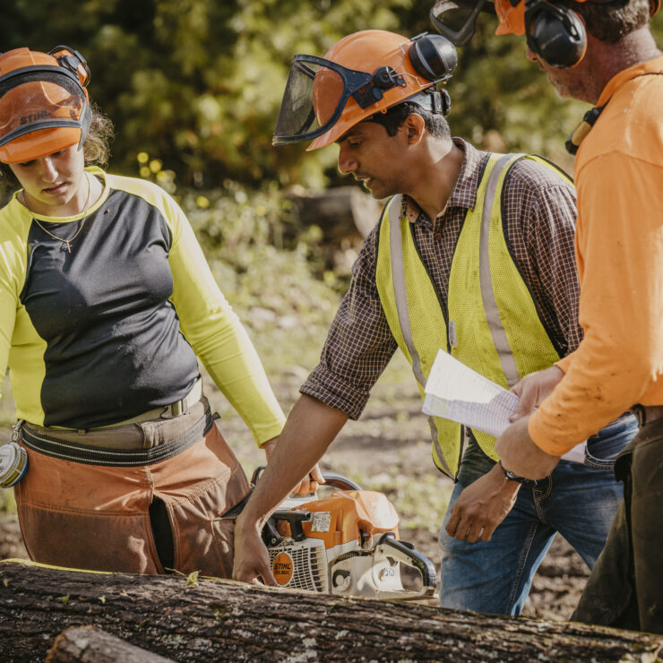 Three people standing next to a log