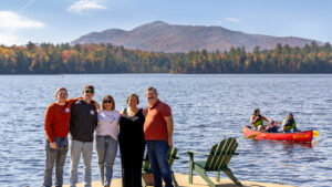 Five people standing on a dock with a canoe in the background