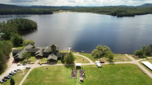 A lawn with an event tent and chairs with a lake beyond it.