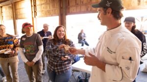 A man in chef whites talking to three people