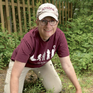 A woman crouching over a dirt patch with a trowel