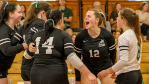 Five people in a group celebrate at a volleyball game