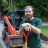 A man standing in front of a front loader with a shovel