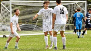 Three soccer players celebrate in front of a goal