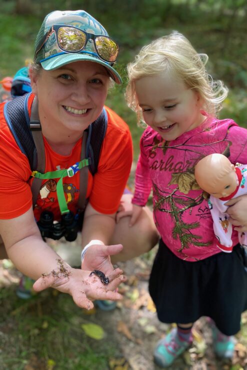 A woman and a girl looking at a salamander